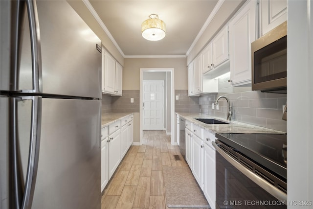 kitchen with backsplash, crown molding, light wood-style floors, white cabinets, and stainless steel appliances