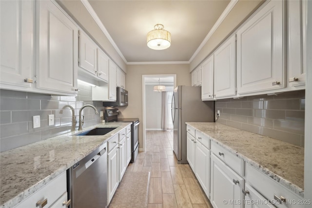 kitchen with a sink, stainless steel appliances, white cabinets, and crown molding