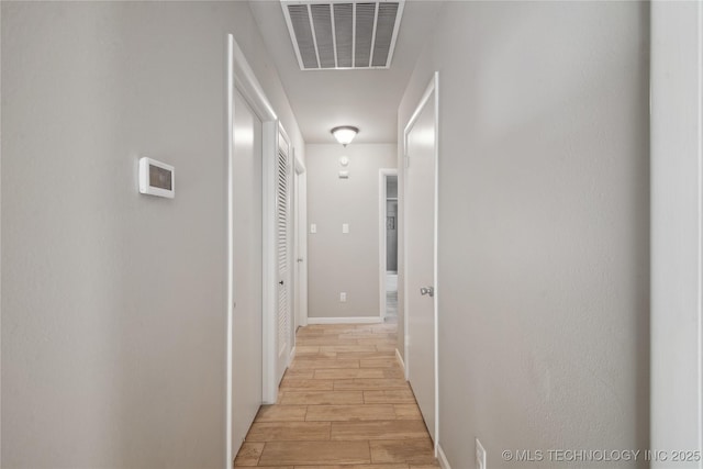 corridor featuring visible vents, baseboards, and wood tiled floor