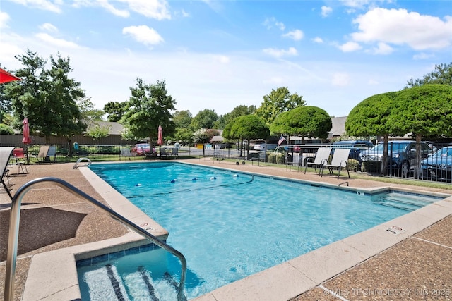 community pool with a patio and fence