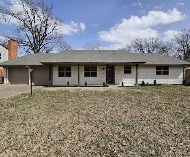 ranch-style home featuring brick siding, an attached garage, concrete driveway, and a front yard