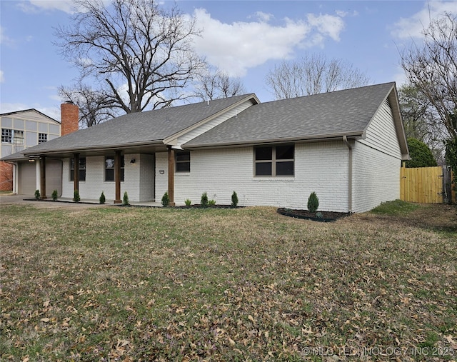 ranch-style house featuring fence, roof with shingles, a front yard, a garage, and brick siding