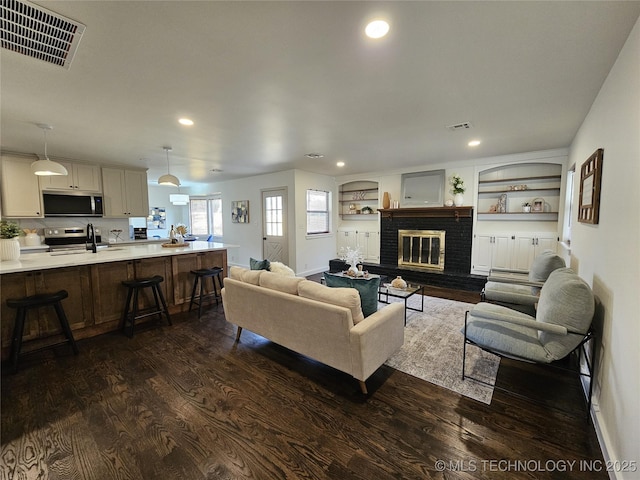 living area with recessed lighting, visible vents, a fireplace, and dark wood-style flooring