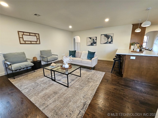 living area featuring visible vents, recessed lighting, dark wood-style floors, and arched walkways