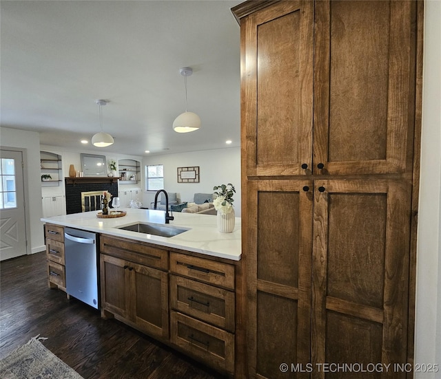 kitchen featuring a sink, hanging light fixtures, dark wood-type flooring, light countertops, and stainless steel dishwasher