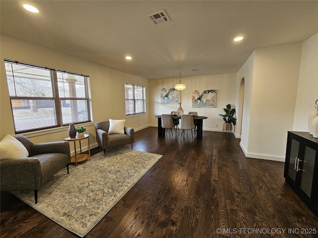 living room featuring recessed lighting, visible vents, arched walkways, and dark wood-style flooring