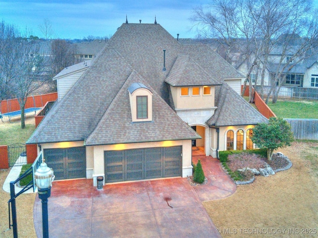 french country home featuring a garage, a front yard, fence, and roof with shingles