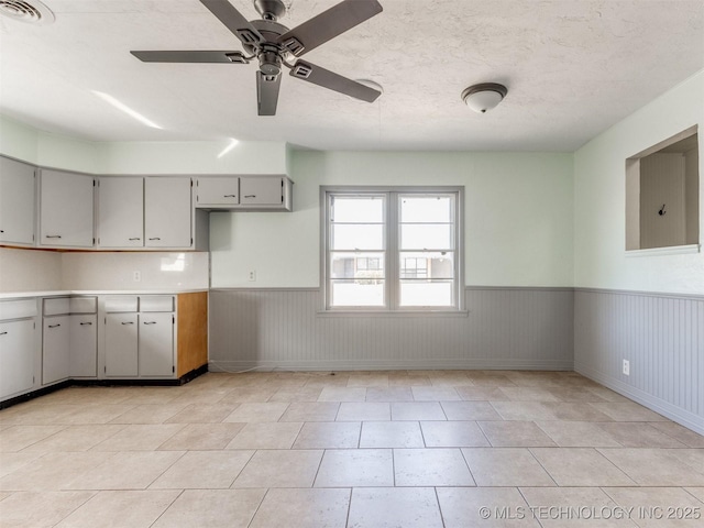 kitchen with visible vents, wainscoting, light countertops, a textured ceiling, and gray cabinetry