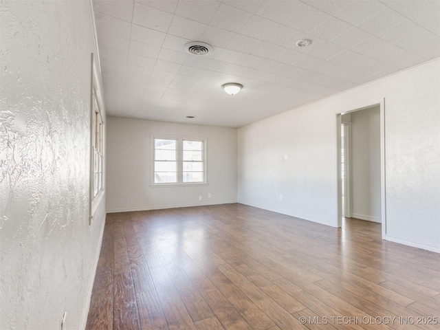 empty room featuring visible vents, baseboards, and wood finished floors