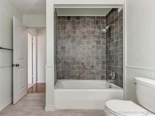 bathroom featuring wainscoting, tub / shower combination, toilet, and wood finished floors