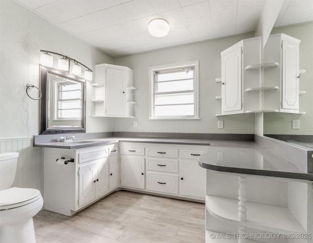 kitchen featuring wainscoting, white cabinets, a sink, and open shelves