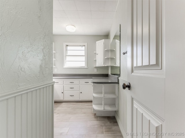 bathroom featuring a wainscoted wall, a textured wall, and vanity