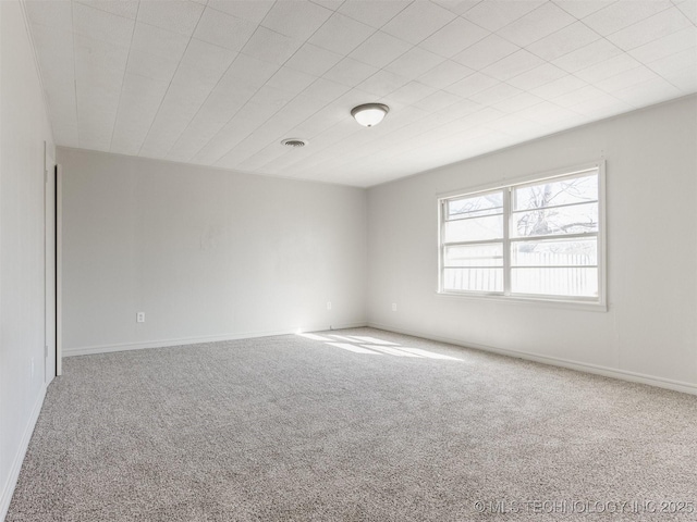 empty room featuring carpet flooring, visible vents, and baseboards