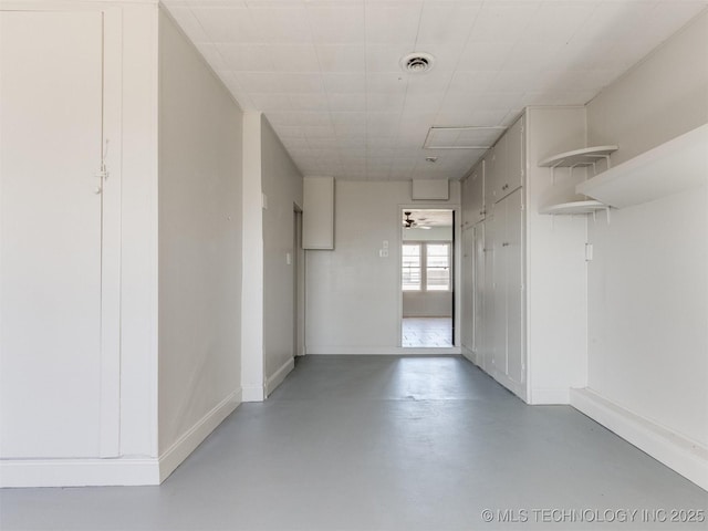 interior space with finished concrete flooring, visible vents, and baseboards