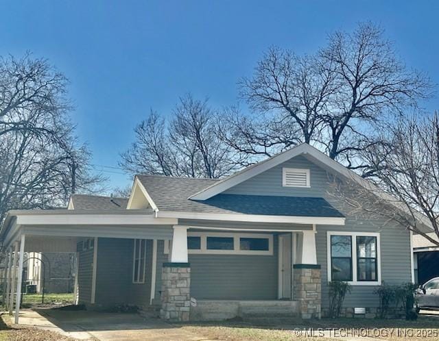 view of front of property with a carport, stone siding, driveway, and roof with shingles