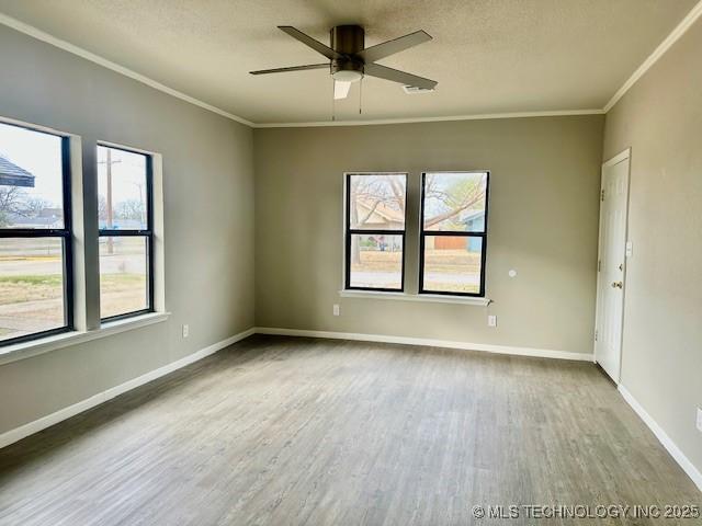 empty room featuring crown molding, ceiling fan, wood finished floors, and baseboards