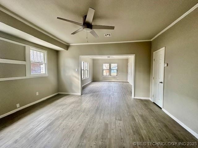 unfurnished living room featuring visible vents, ornamental molding, a ceiling fan, wood finished floors, and baseboards