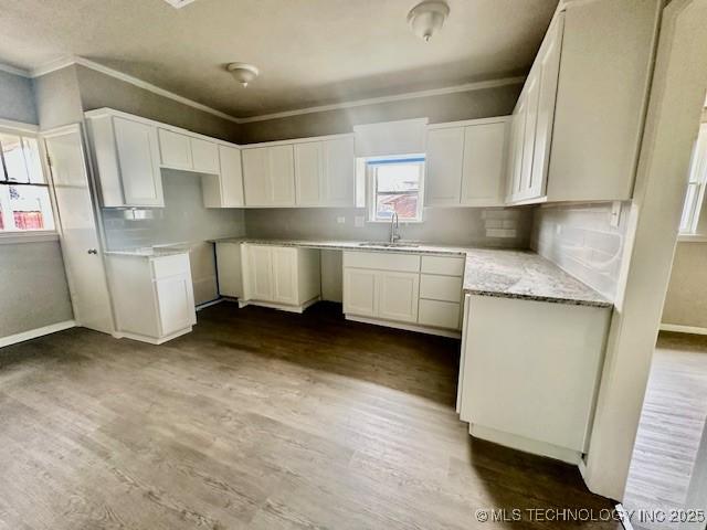 kitchen with light stone countertops, crown molding, white cabinetry, and dark wood-type flooring