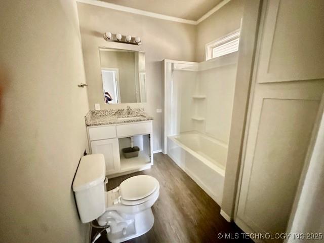 full bath featuring toilet, wood finished floors, bathtub / shower combination, crown molding, and vanity