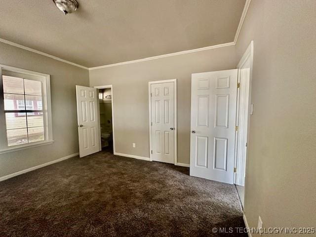 unfurnished bedroom featuring baseboards, dark carpet, and crown molding