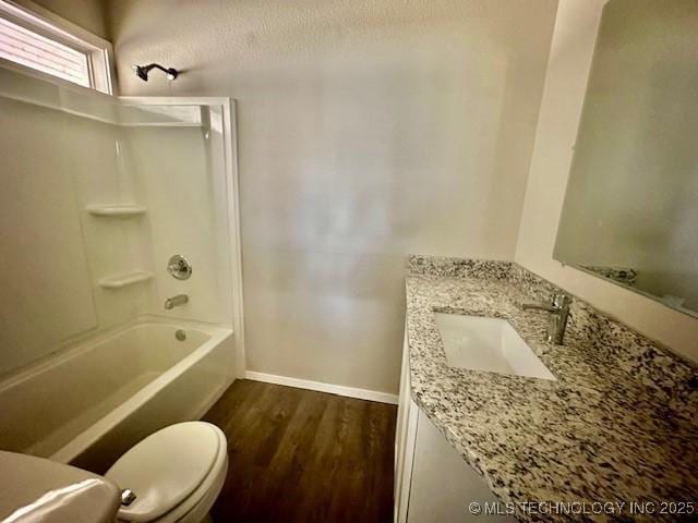 bathroom with bathtub / shower combination, toilet, wood finished floors, vanity, and baseboards