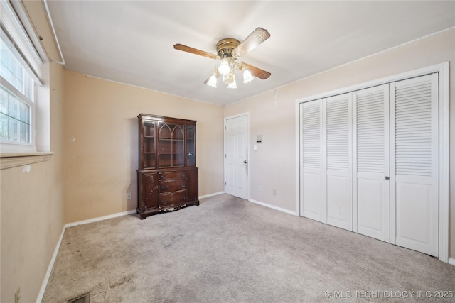 unfurnished bedroom featuring ceiling fan, carpet floors, a closet, and baseboards