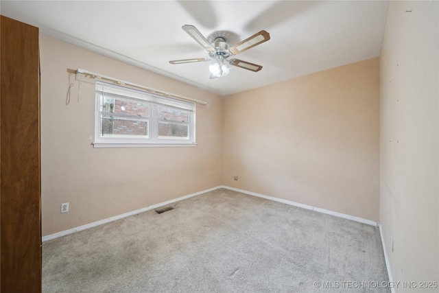 carpeted spare room featuring a ceiling fan, visible vents, and baseboards