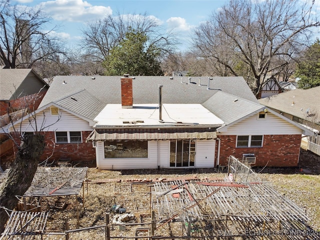 back of property featuring brick siding, a chimney, and a shingled roof