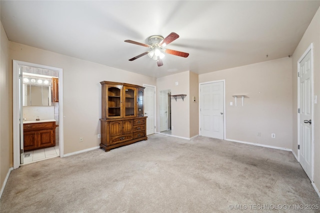 unfurnished bedroom featuring light carpet, a ceiling fan, baseboards, and connected bathroom