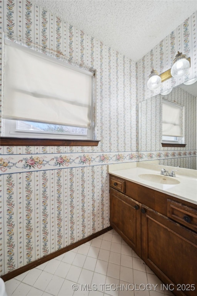 bathroom with plenty of natural light, a textured ceiling, vanity, and wallpapered walls