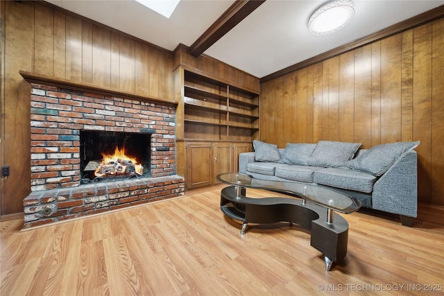 living room with light wood finished floors, a fireplace, beamed ceiling, and wood walls