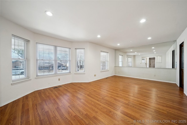 unfurnished living room with light wood-type flooring, baseboards, visible vents, and recessed lighting