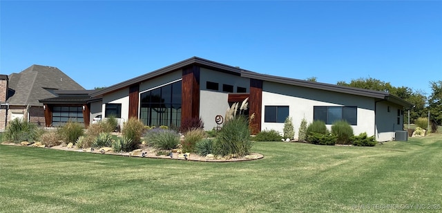 view of property exterior with stucco siding, central AC unit, and a yard