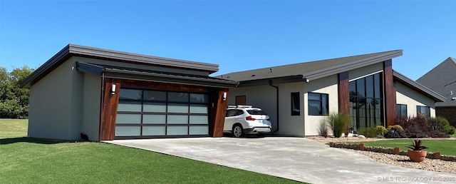 view of front facade with a garage, a front yard, concrete driveway, and stucco siding