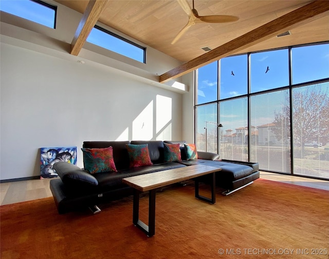 living area featuring a towering ceiling, floor to ceiling windows, and a ceiling fan