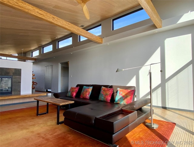 living area featuring a towering ceiling, wooden ceiling, beam ceiling, and a tile fireplace