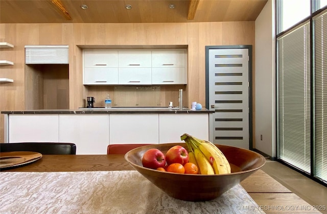 kitchen featuring dark countertops, wooden ceiling, white cabinets, and modern cabinets