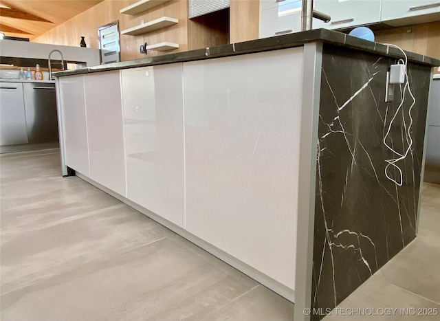 interior space with dark countertops, modern cabinets, white cabinetry, and a sink