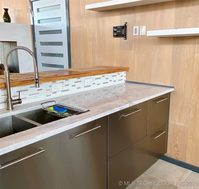 kitchen featuring tasteful backsplash, modern cabinets, a sink, and light stone counters