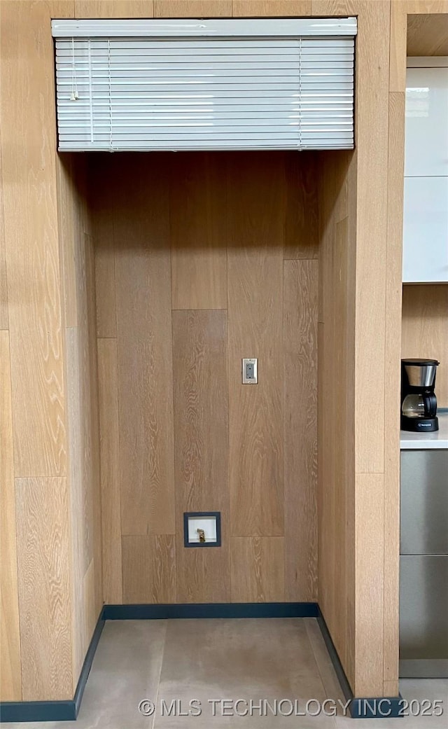 laundry area with wood walls