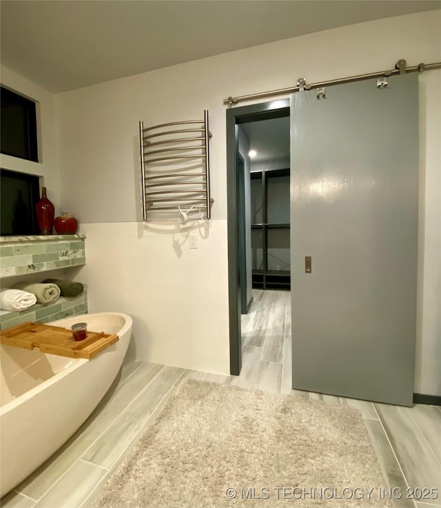 bathroom featuring radiator, a freestanding tub, and tile walls