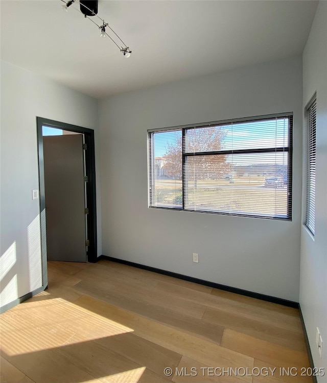 empty room with baseboards and wood finished floors