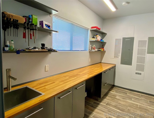 kitchen with open shelves, butcher block counters, a sink, and electric panel