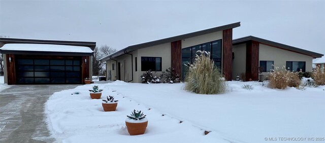 view of snow covered exterior with a garage and stucco siding