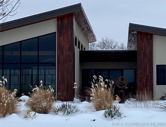 view of snowy exterior with stucco siding