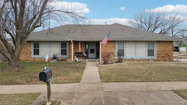 ranch-style house featuring brick siding, a front yard, and a shingled roof