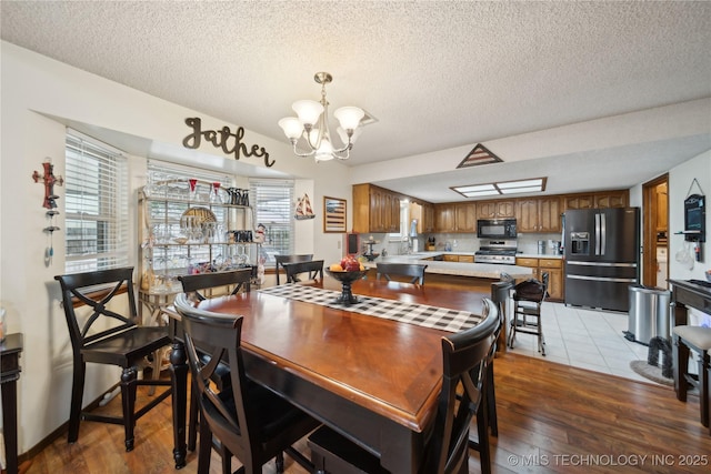 dining area with an inviting chandelier, light wood-style floors, and a textured ceiling