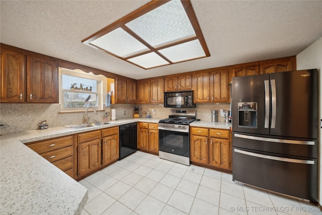 kitchen with brown cabinetry, black appliances, light countertops, and a sink