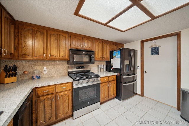 kitchen with fridge with ice dispenser, brown cabinets, black microwave, light countertops, and stainless steel range with gas stovetop