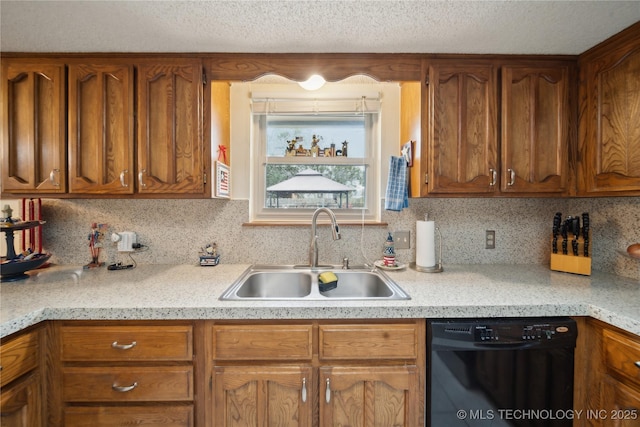 kitchen with a sink, decorative backsplash, light countertops, black dishwasher, and brown cabinets